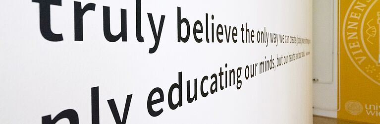 a hallway at the Center for Teacher Education with a long quote on the wall; foregrounded are the letters 