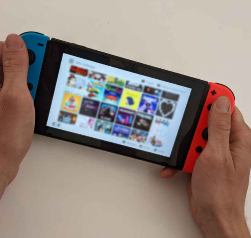 Zwei Hände, die eine Nintendo-Switch halten